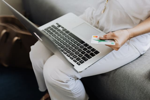 person holding a laptop and credit card