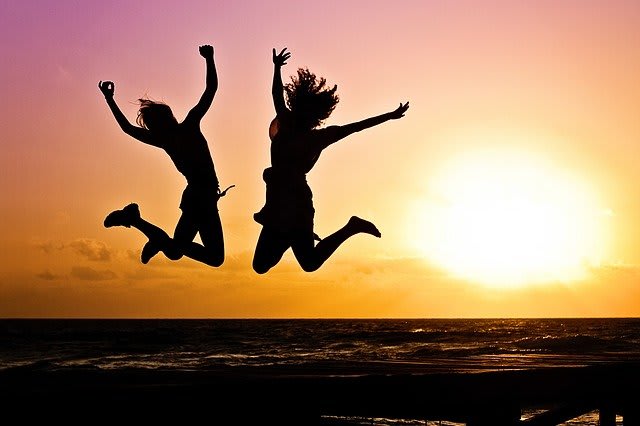 people jumping on a beach during a sunset