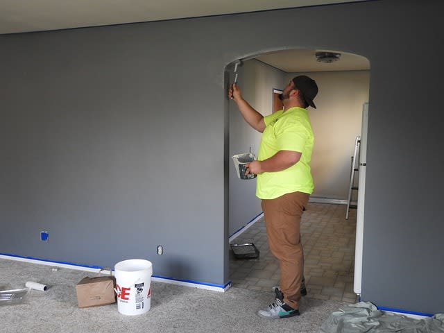 person painting a wall in a house