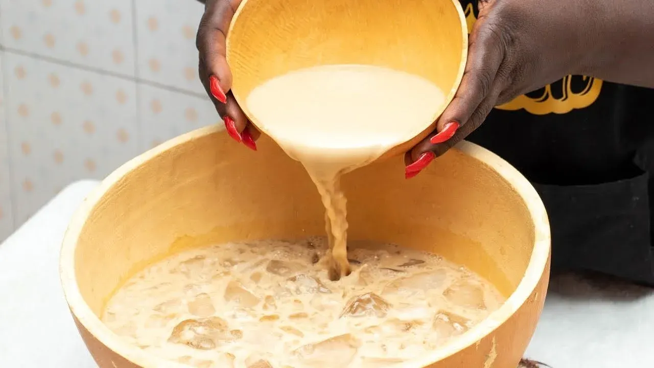 A Ghanaian market seller measuring fresh ginger, a central ingredient in lamugin