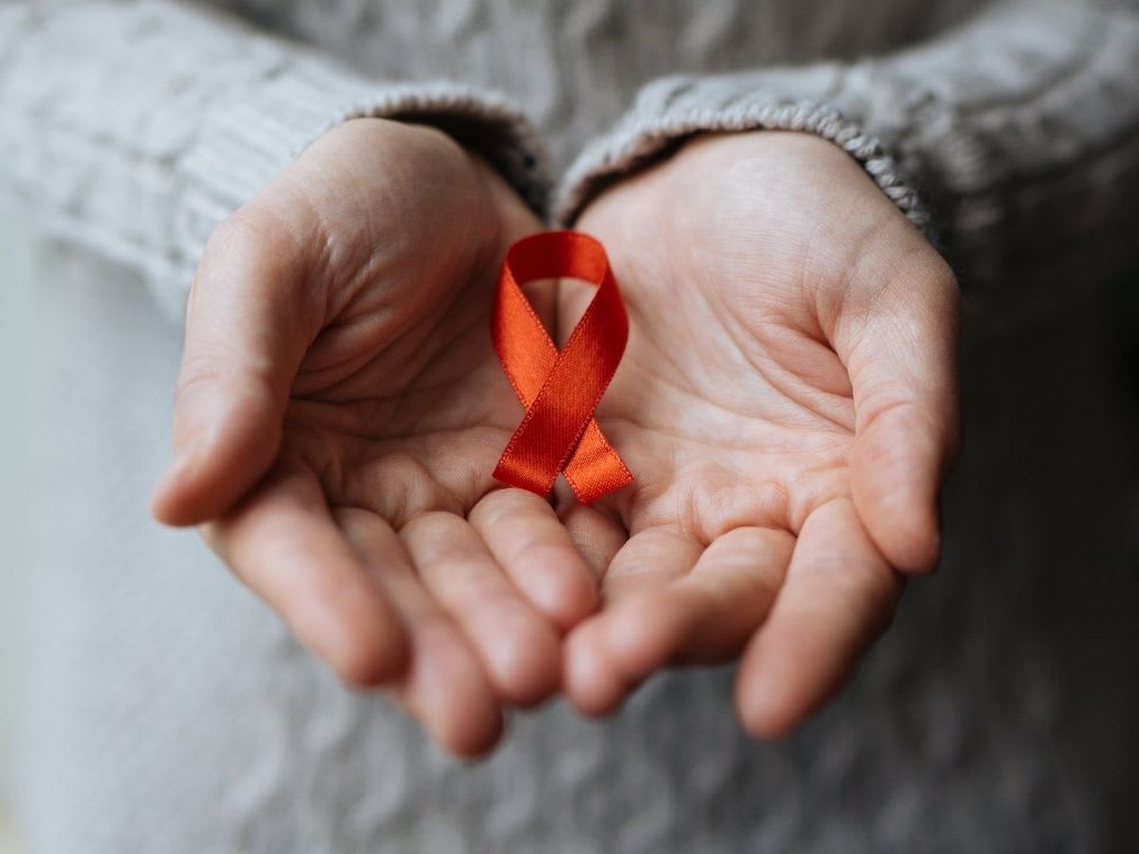 A person holding an orange ribbon in their hands.