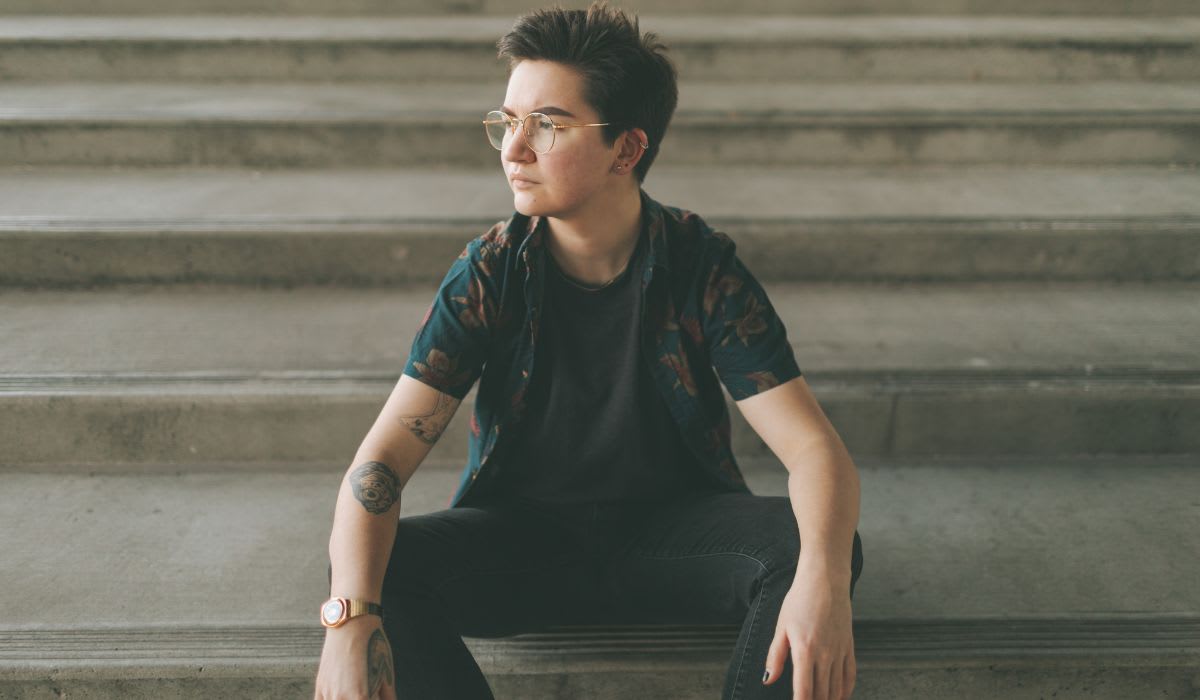 trans person sitting on some stairs in the street