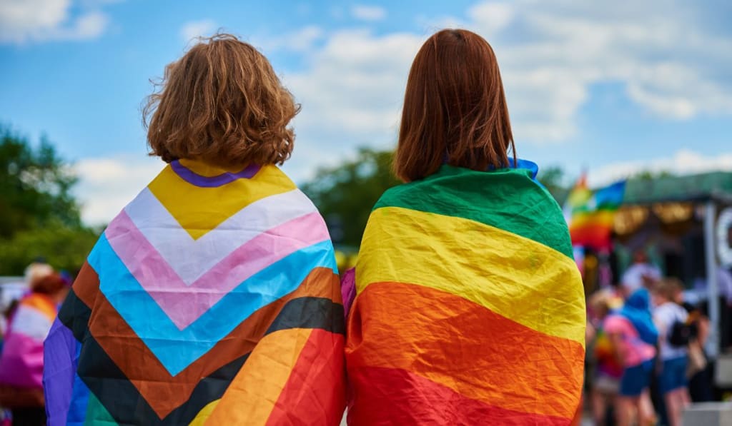 Two women with LGBTQ rainbow flags on pride demonstration