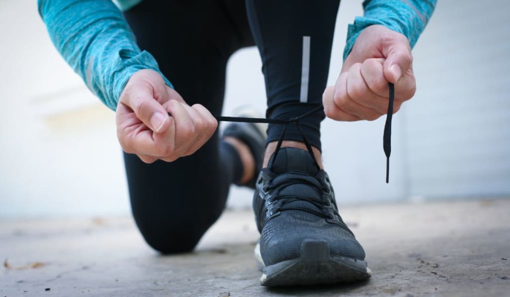 Person tying the shoelaces of a running shoe.