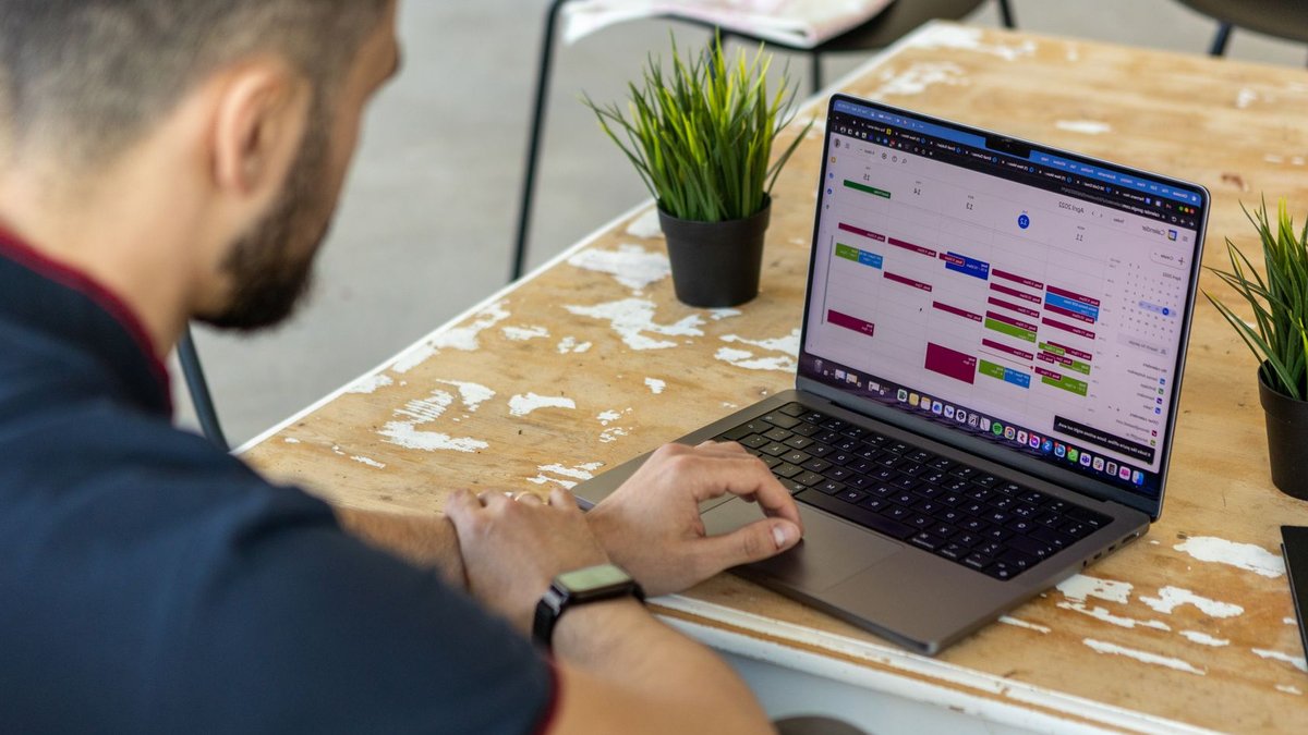 Smart strategies boost workplace efficiency Man working remotely at a desk with a laptop open to a calendar app.