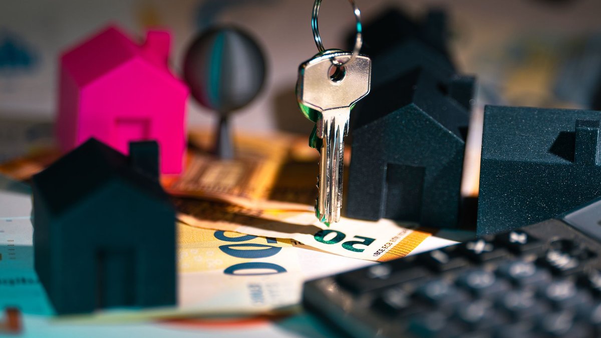 A symbolic representation of real estate finance featuring keys, model houses, and euro banknotes.