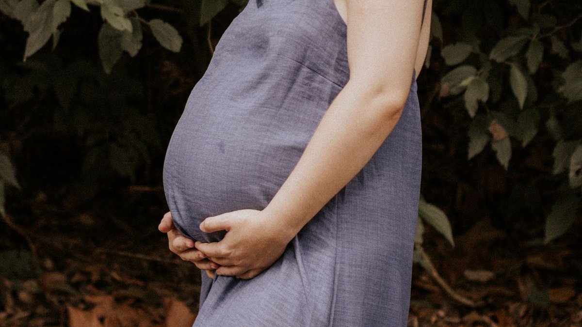 New ATA guidelines on thyroid disease in pregnancy and preconception A woman in a blue dress enjoying nature during pregnancy, standing outdoors.