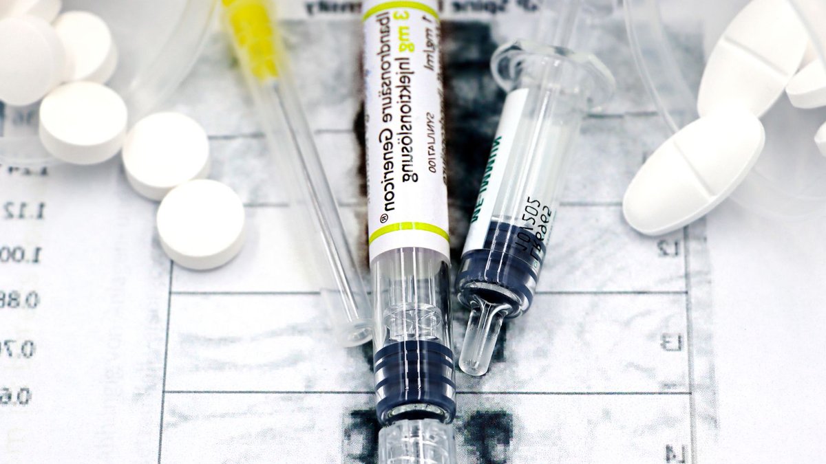 Close-up of syringes and pills on a bone density exam sheet, depicting osteoporosis treatment.