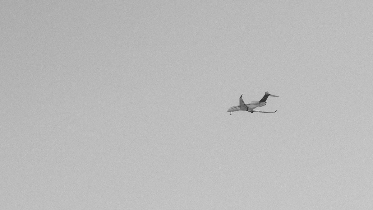 US travel warnings trigger UAE flight disruptions Black and white photo of a jet airplane in flight against a clear sky.