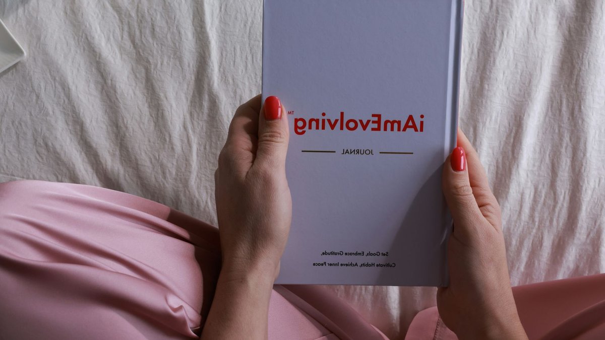 Person in pink pajamas holding a journal, embracing a cozy and mindful morning routine indoors.