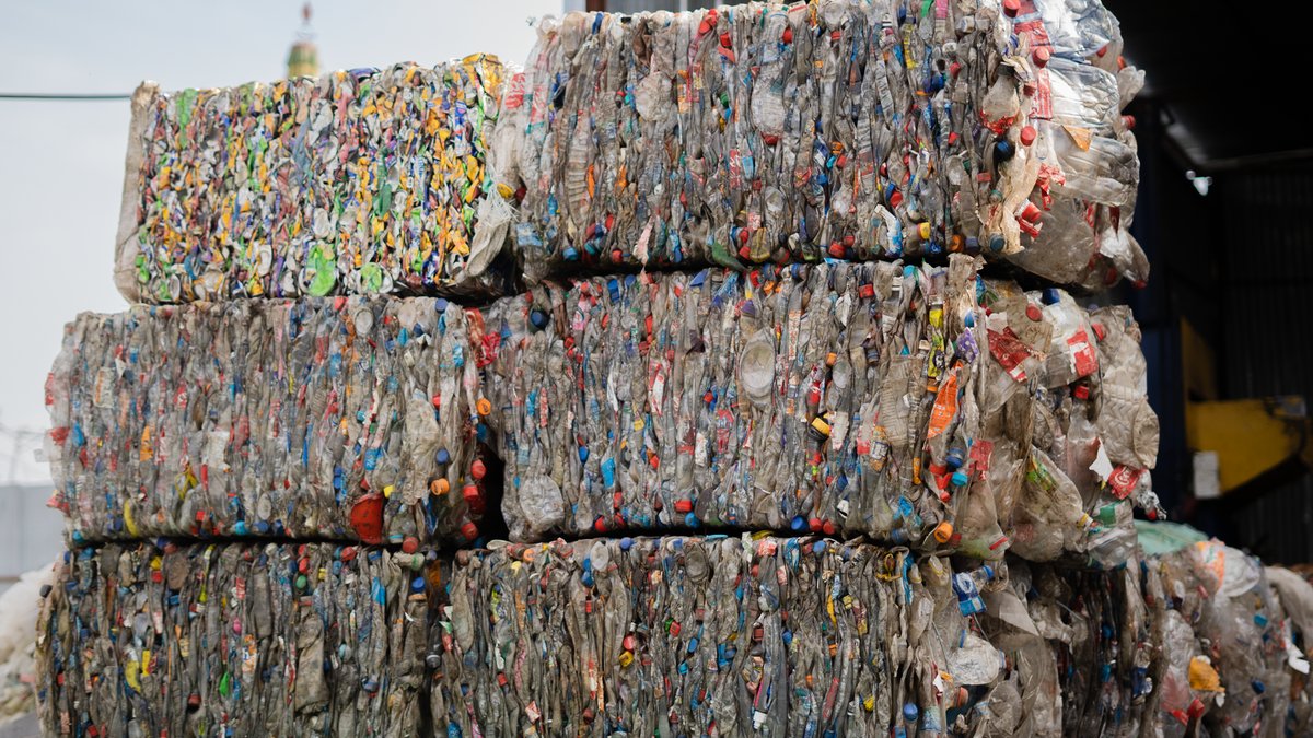 Emirates Shipping bans plastic waste cargo Stacked compressed plastic bottles at a recycling facility, ready for processing.