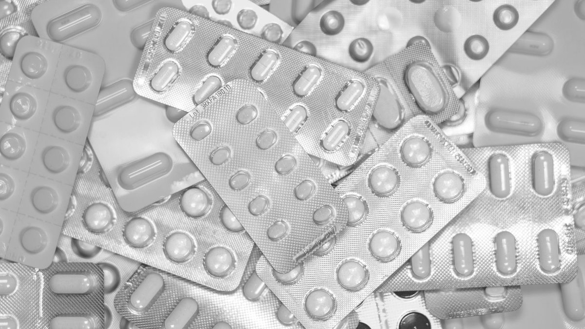 Pharmaceutical sector seeks new regulations Monochrome close-up of assorted blister packs with pills, highlighting pharmaceutical packaging.