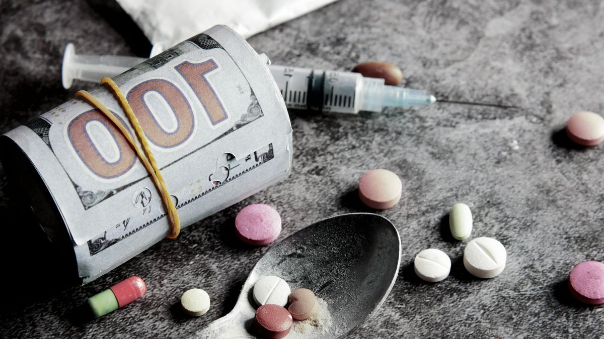 Symbolic representation of drug addiction and financial cost with pills and money.
