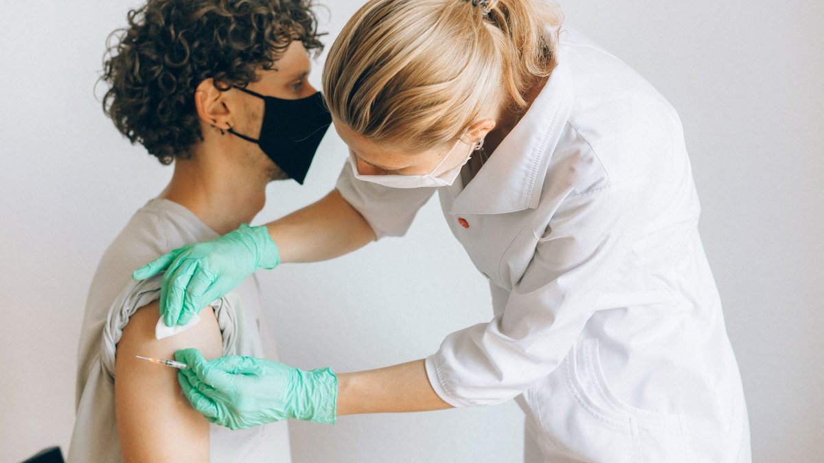 Bangladesh battles deadly measles and dengue surge A healthcare worker gives a vaccine shot to a patient wearing a mask, highlighting medical safety and health precautions.