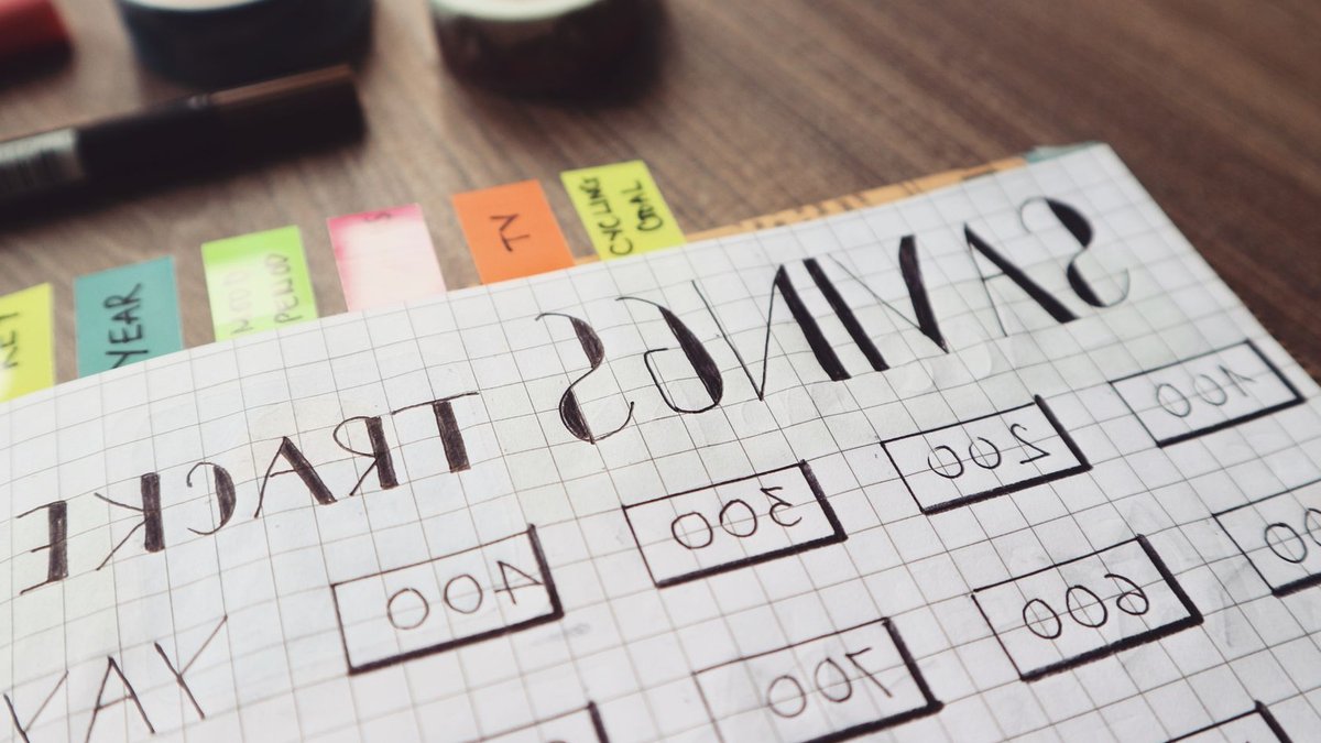 Close-up of a handmade savings tracker with colored tabs on a wooden table, ideal for financial planning visuals.