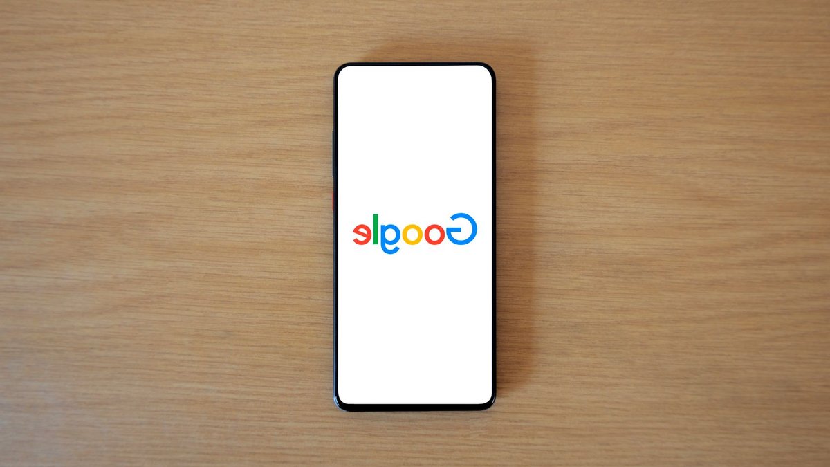 Google Launches AI Chips into Space for Durability Test A smartphone displaying the Google homepage on a wooden surface, viewed from above.