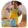 Little girl with curly pig tails and bright yellow corduroy overalls playing with a a card from a Tonieplay game next to her blue Toniebox 2.