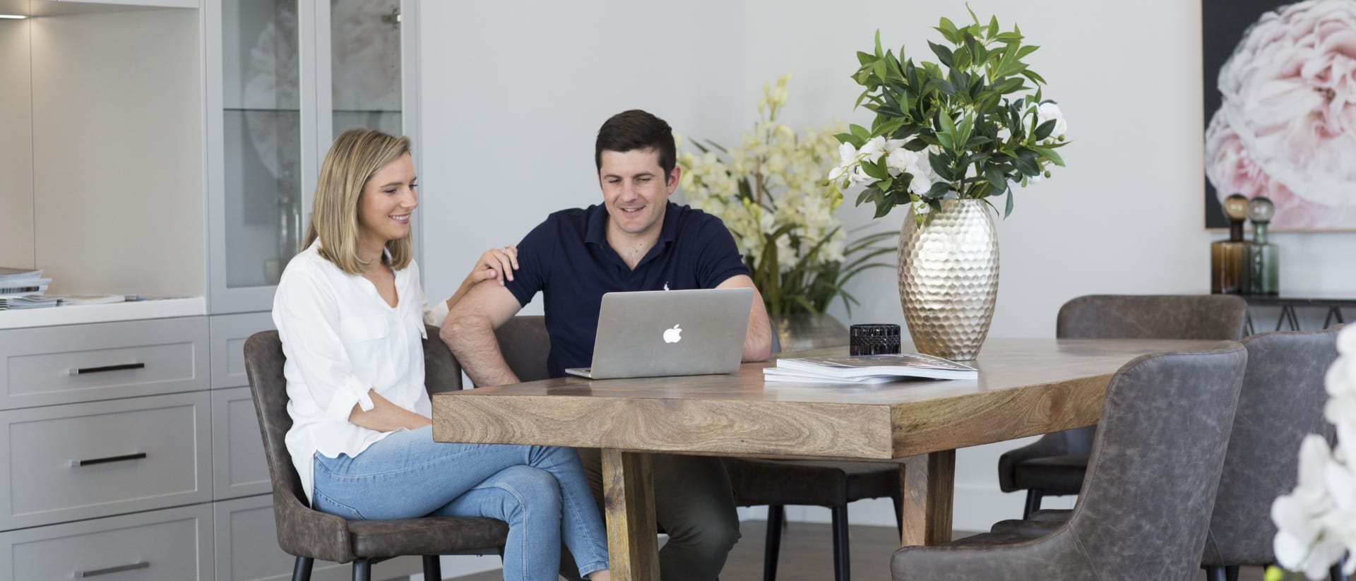 Two people going over a laptop together at a dining table