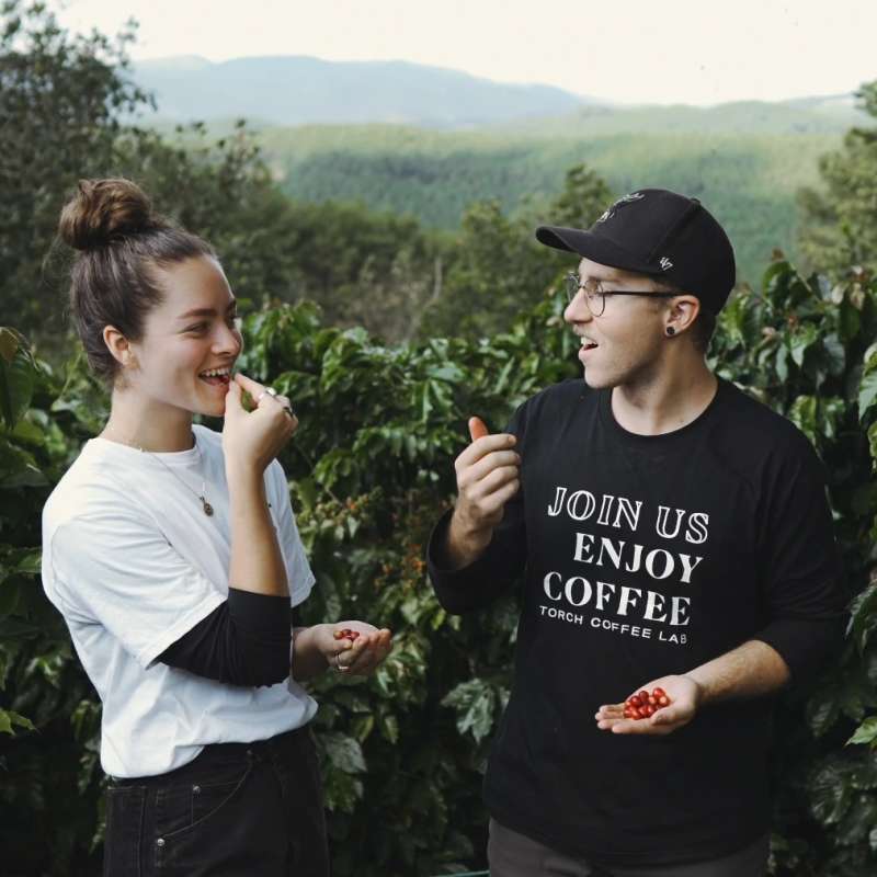 Founders Paul and Summer Orr enjoying green coffee in a Laos coffee field.