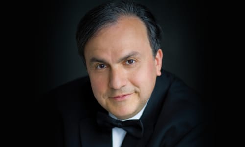 Yefim Bronfman headshot, wearing a black tuxedo, against a black background