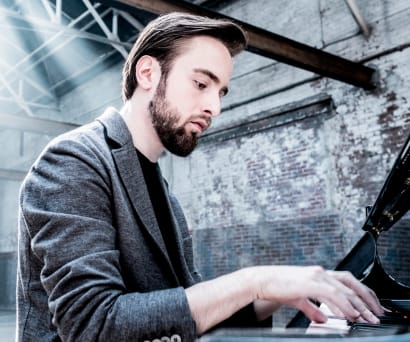 Daniil Trifonov playing the piano in an empty building