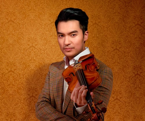 Ray Chen with his violin against an orange background