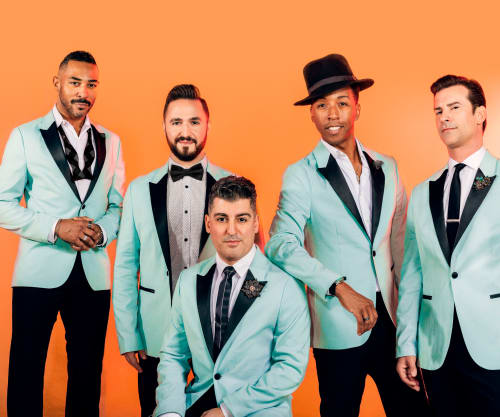 Members of The Doo Wop Project in matching blue blazers against an orange backdrop