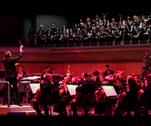 Steven Reineke conducting the TSO with a choir under red lighting