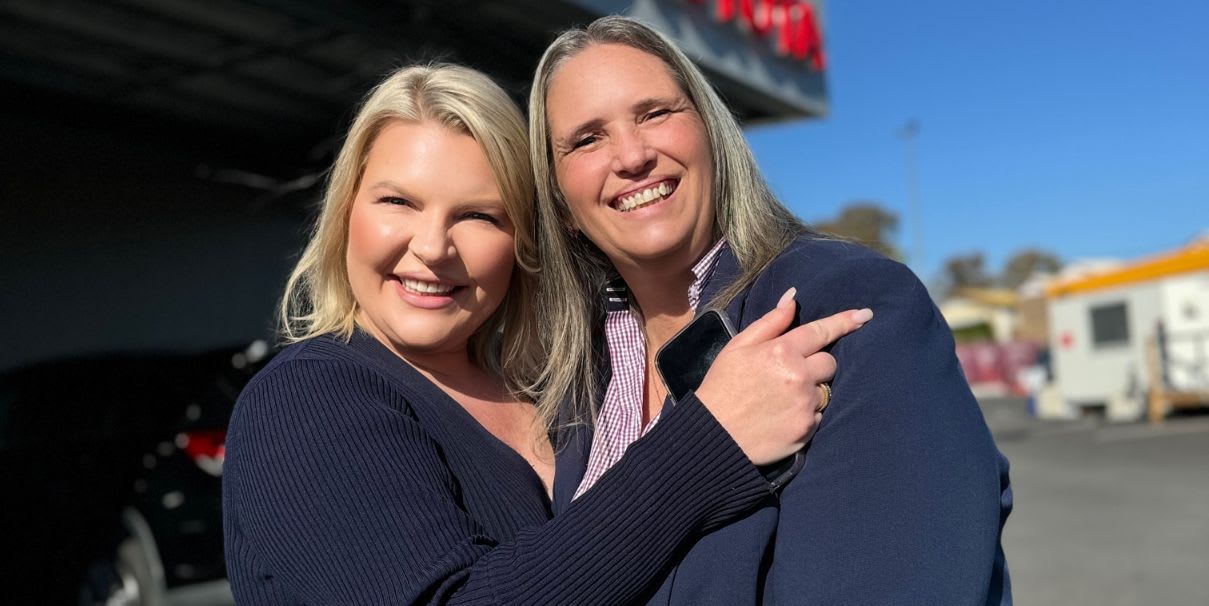 Vicki Baldwin standing with Kate Jones in front of Downtown Toyota