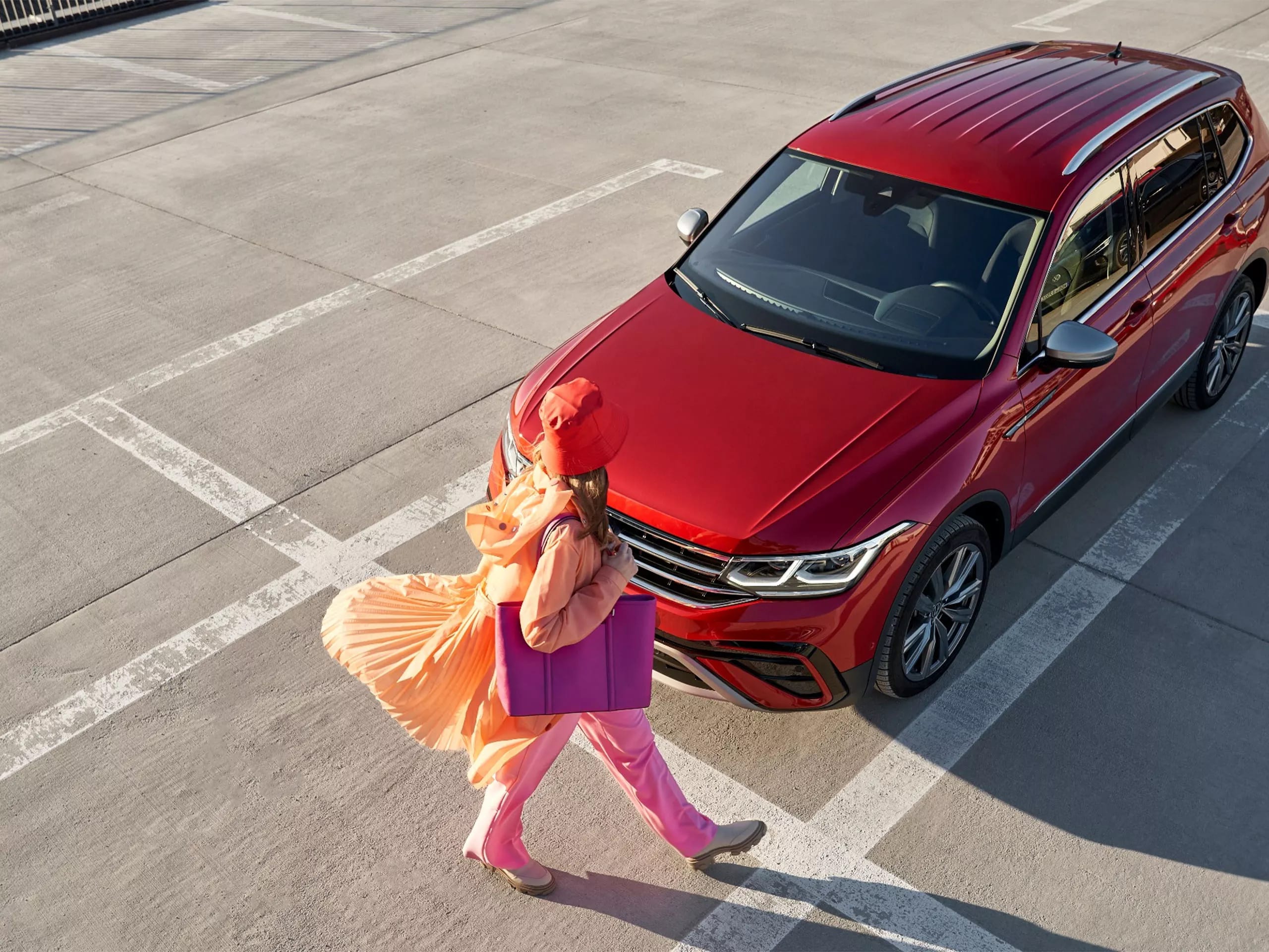 Woman walking in front of red VW car