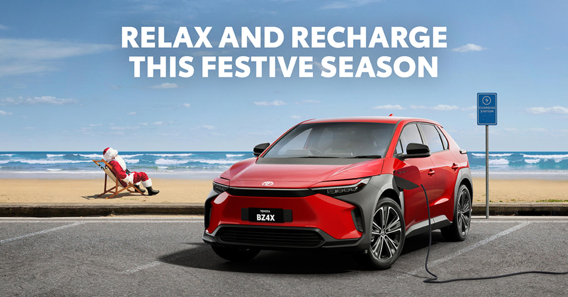 An ocean-front all-electric BZ4x charging by the beach-side, with Santa sun bathing on the beach.&nbsp;