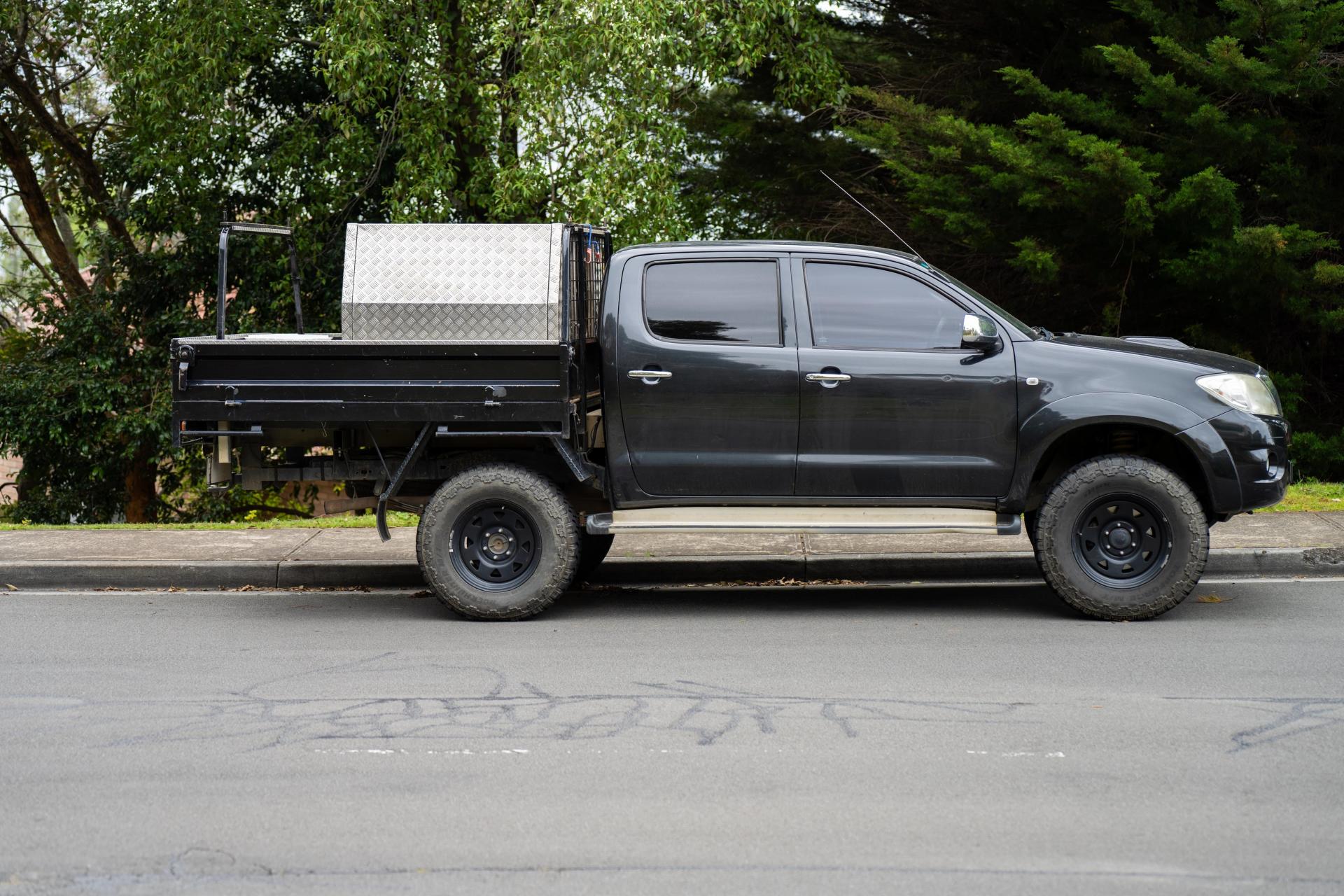 &nbsp; Black dual cab 4WD ute with tray and toolboxes parked on suburban street, perfect for tradies and off-road enthusiasts needing work and weekend versatility