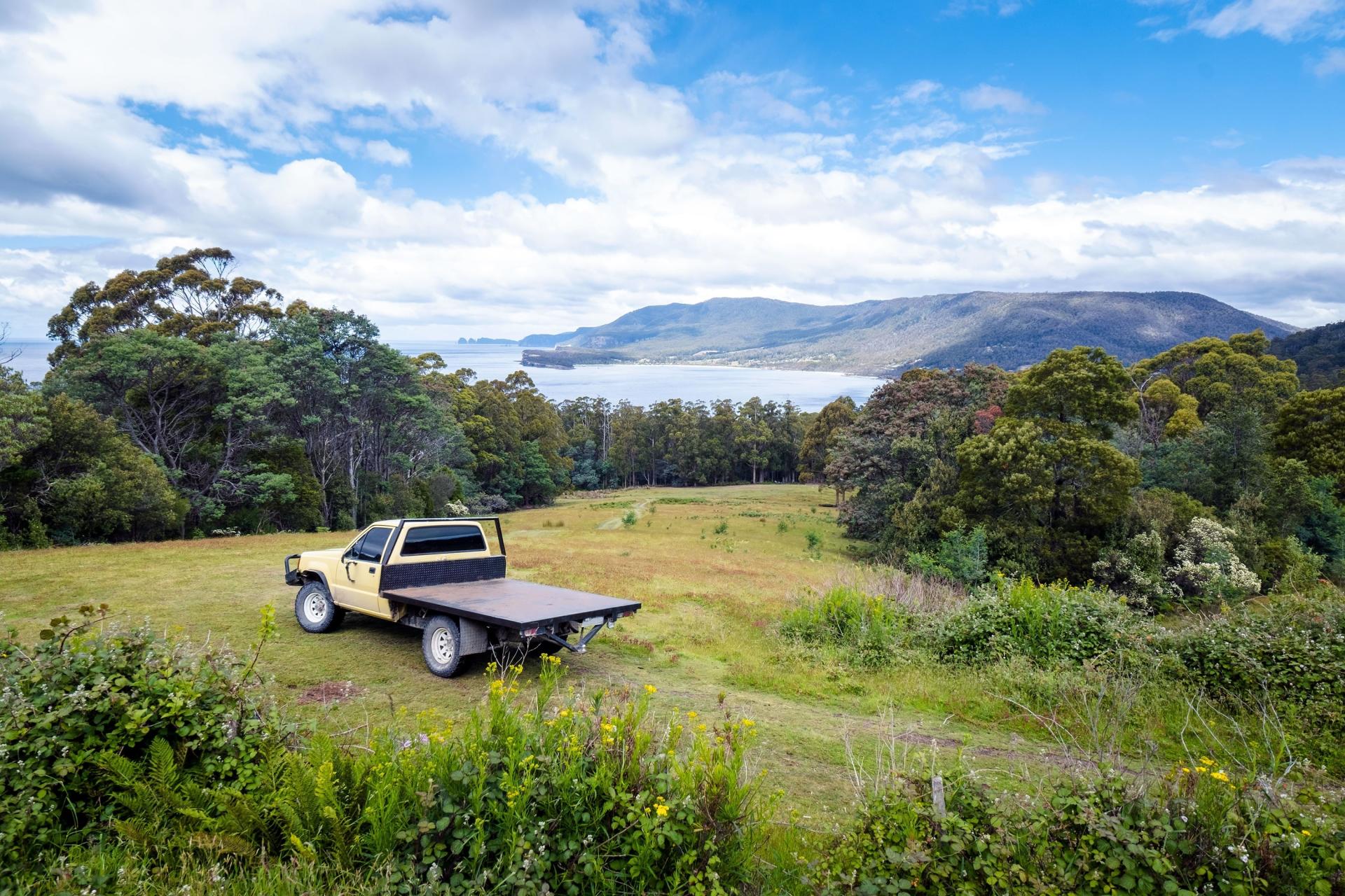 &nbsp; Flat tray 4WD parked on grassy hill overlooking forest and coastline&nbsp;&nbsp;