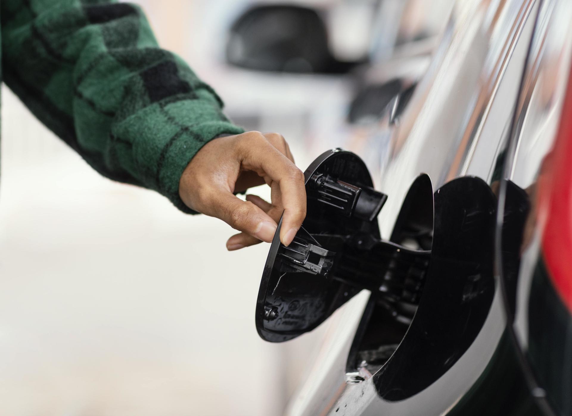 &nbsp; Person checking car fuel cap as a possible cause of check engine light warning&nbsp;&nbsp;