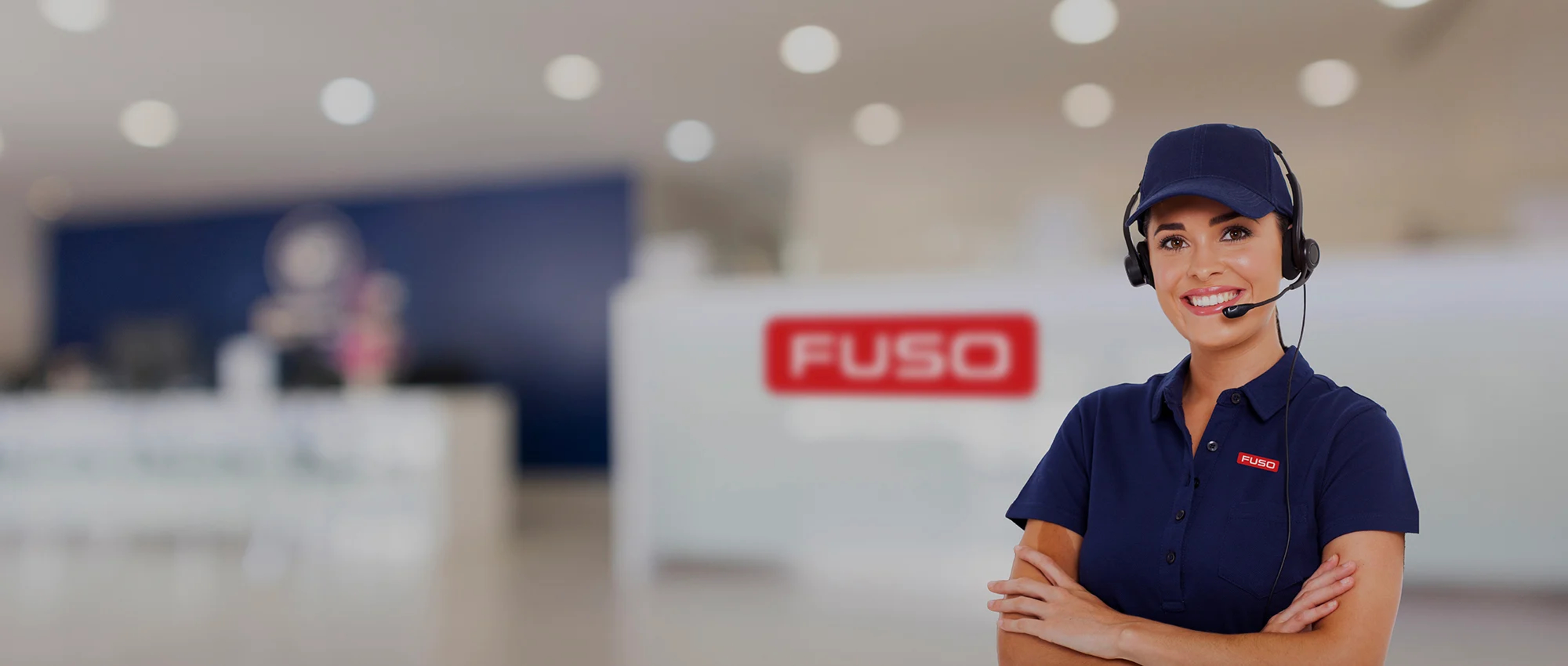 A FUSO customer service representative standing with her arms crossed in front of a blurred background.