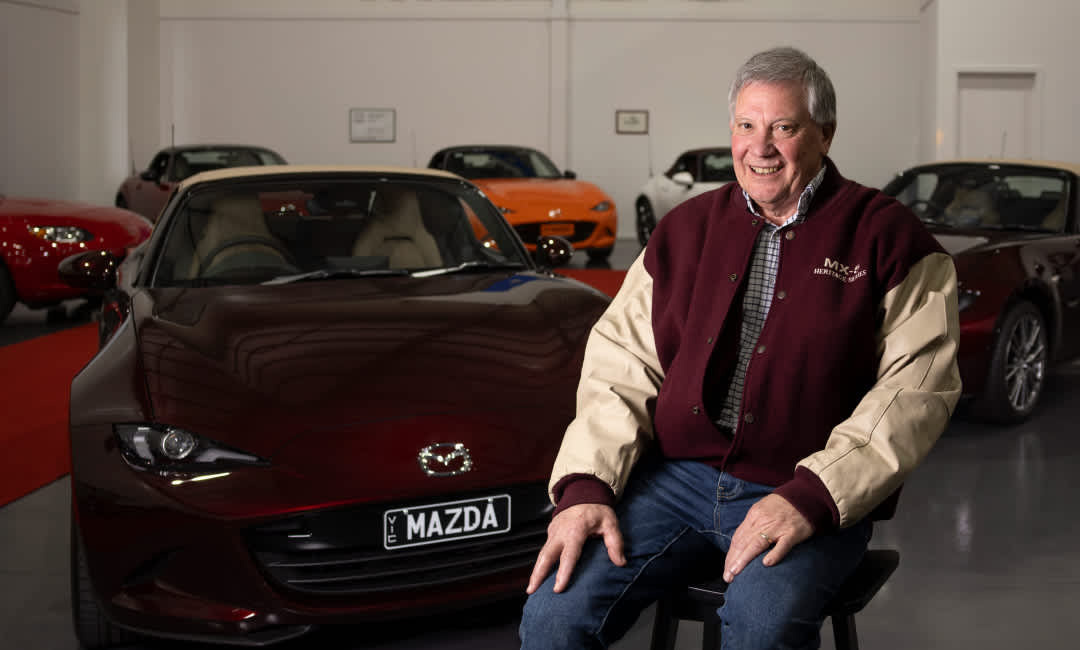 Alan Wilson in front of a Mazda MX-5 35th Anniversary Edition with other MX-5 models displayed in the background.