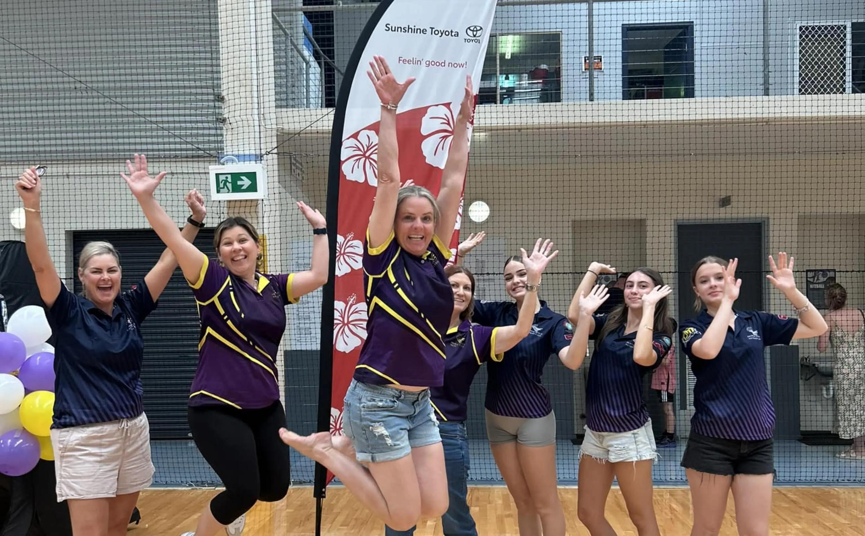 netball team jumping with sunshine toyota banner in background