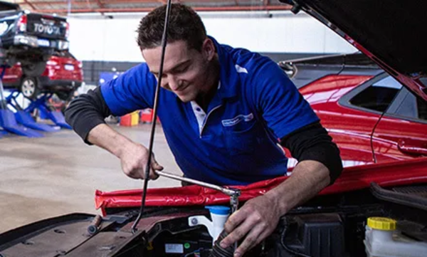 Mechanic smiling under car bonnet