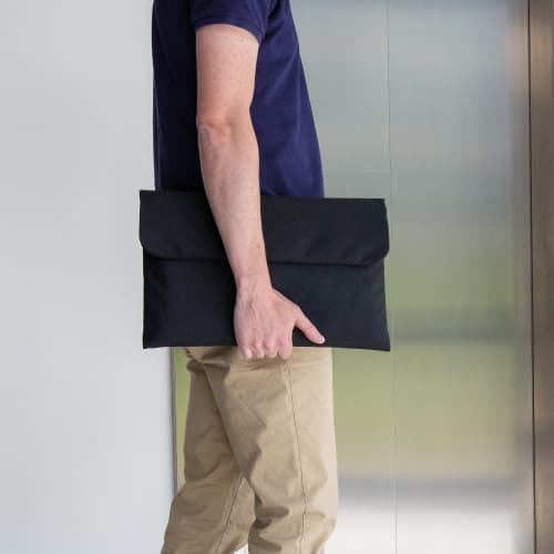 A lifestyle image of the Magnetic Closing 15.6" Laptop Sleeve in Black being used