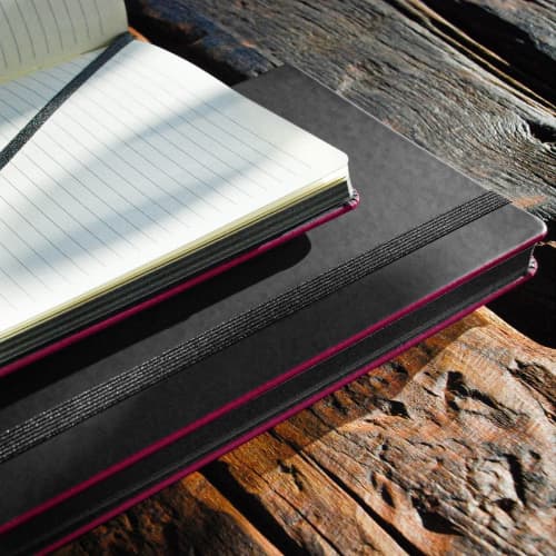 Lifestyle image of the Black Laser Notebooks with a design from Total Merchandise