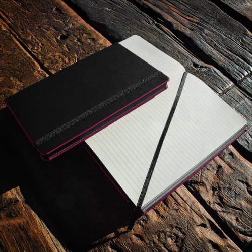 Lifestyle image of the Black Laser Notebooks with a design from Total Merchandise