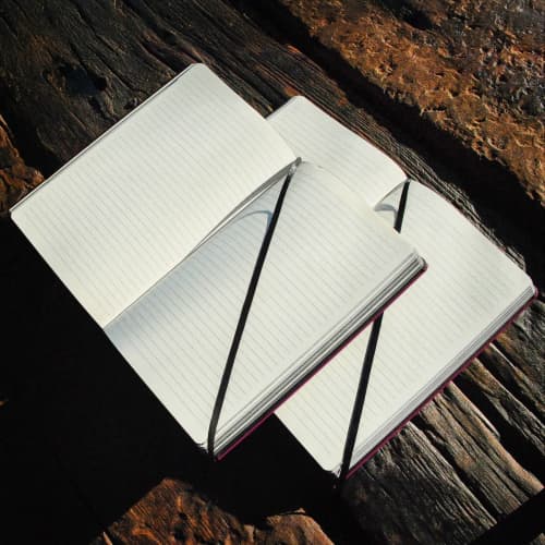 Lifestyle image of the Black Laser Notebooks with a design from Total Merchandise