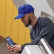 Lifestyle image of the Impact 5 Panel Recycled Cotton Cap with AWARE™ Tracer from Total Merchandise
