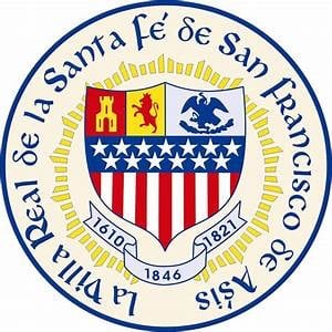 a red, yellow, gray and blue logo mark depicting the City of Española's seal