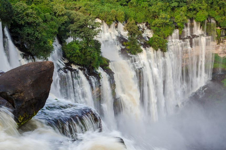 Kalandula Falls in full flow with lush green rain forest, rocks and spray