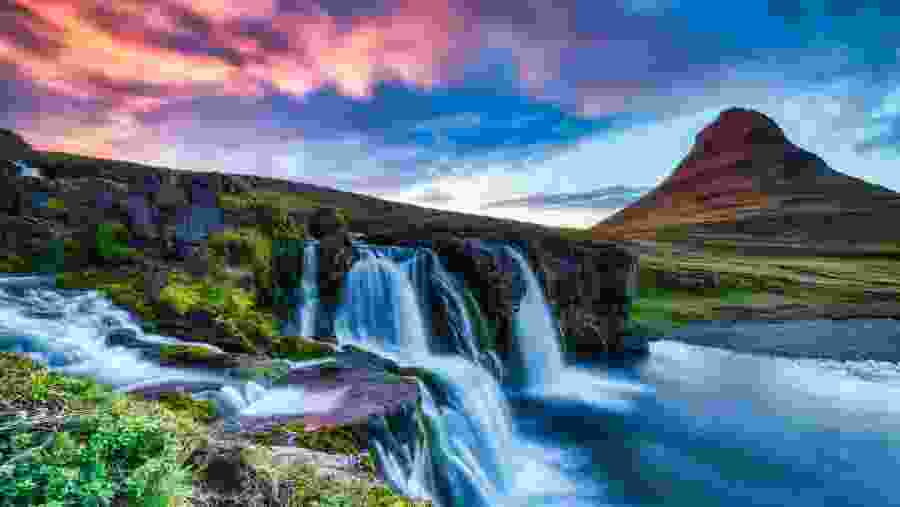 Kirkjufell and the nearby waterfall bathed in the warm hues of sunset