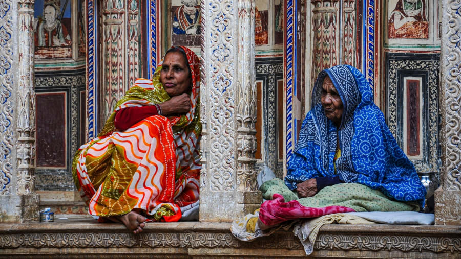Desert women sit their old beautiful haveli