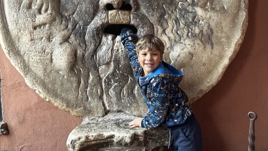 A child posing near a Roman statue