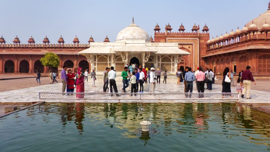 People standing in front of Tomb of Salim Chishti in the courtyard of Jama Masjid, Fatehpur Sikri, India. The tomb is famed as one of the finest examples of Mughal architecture.