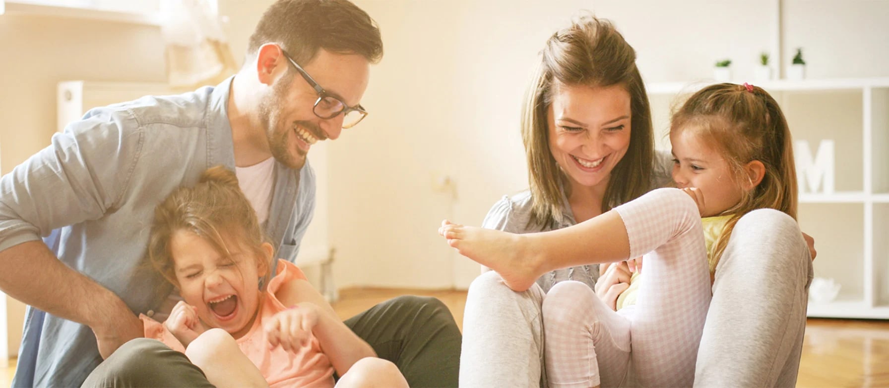 A happy family of four - two adults and two children - sharing a joyful moment together in a warm, cozy home setting.